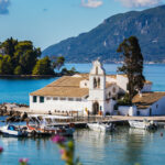 White-washed Vlacherna Monastery in the middle of a bay with mountains in the background