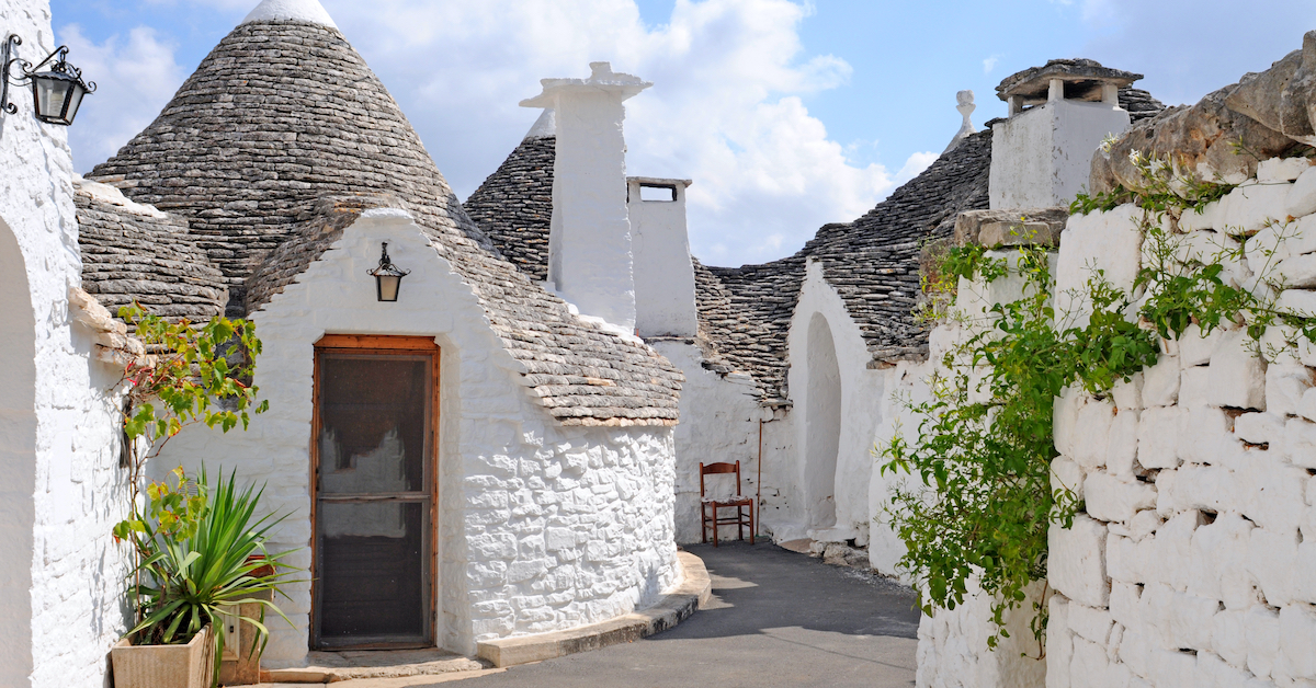 Round white stone houses with conical gray stone roofs in Alberobello, Italy