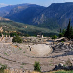 The amphitheater of Delphi in the foreground with the Temple of Apollo in the middle ground and mountains in the background