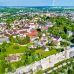 Aerial view of the small city of Provins, France with a large wall forming a boundary along one side and greenery and stone buildings in the center