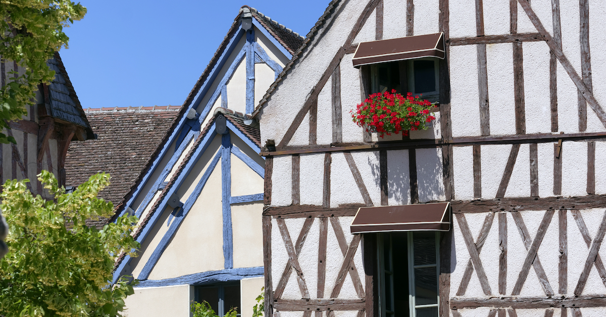 Stone houses with wooden medieval trim and bright reds flowers in planter boxes below the windows