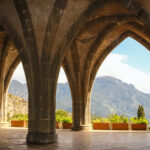 View through a series of stone archways out toward mountains and green plants of the Villa Cimbrone Gardens