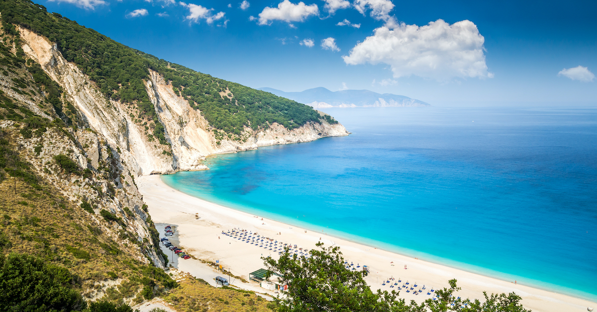 View overlooking Myrtos Beach in Kefalonia, Greece, a white beach horseshoed in by rocky greenery around light blue water