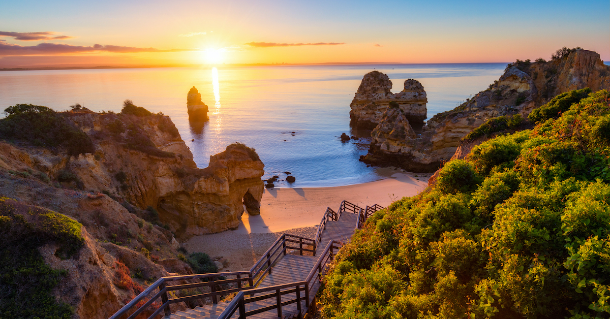 Steps leading down to the rocky Praia do Camilo in Algarve, Portugal at sunrise