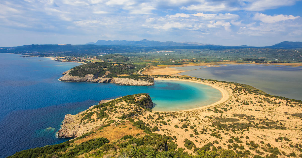 Aerial view of Voidokilia Bay on one side of a strip of beach with Gialova Lagoon on the other where Voidokilia Beach in Greece, one of the best beaches in Europe, is found