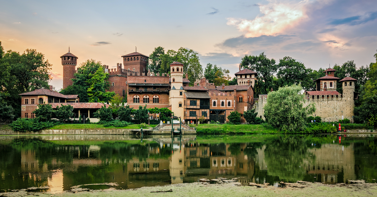 View across a green pond of Borgo Medievale Turin, a small medieval village of stone walls and towers