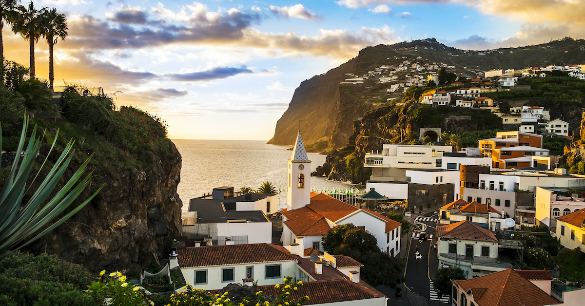 Sunset over a cliffside town in Madeira, one of the best Portugal honeymoon destinations