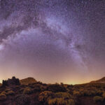 Bright night sky with the Milky Way visible over a desert landscape