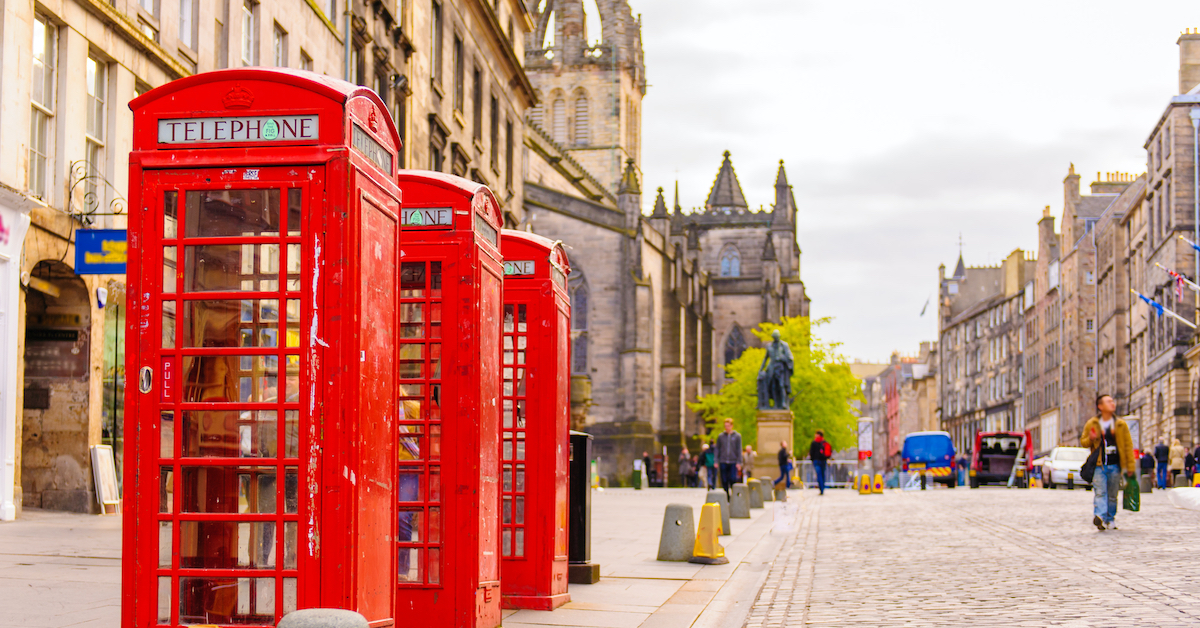 Three red telephone booths on a beige stone road in Edinburgh, one of the best United Kingdom honeymoon destinations