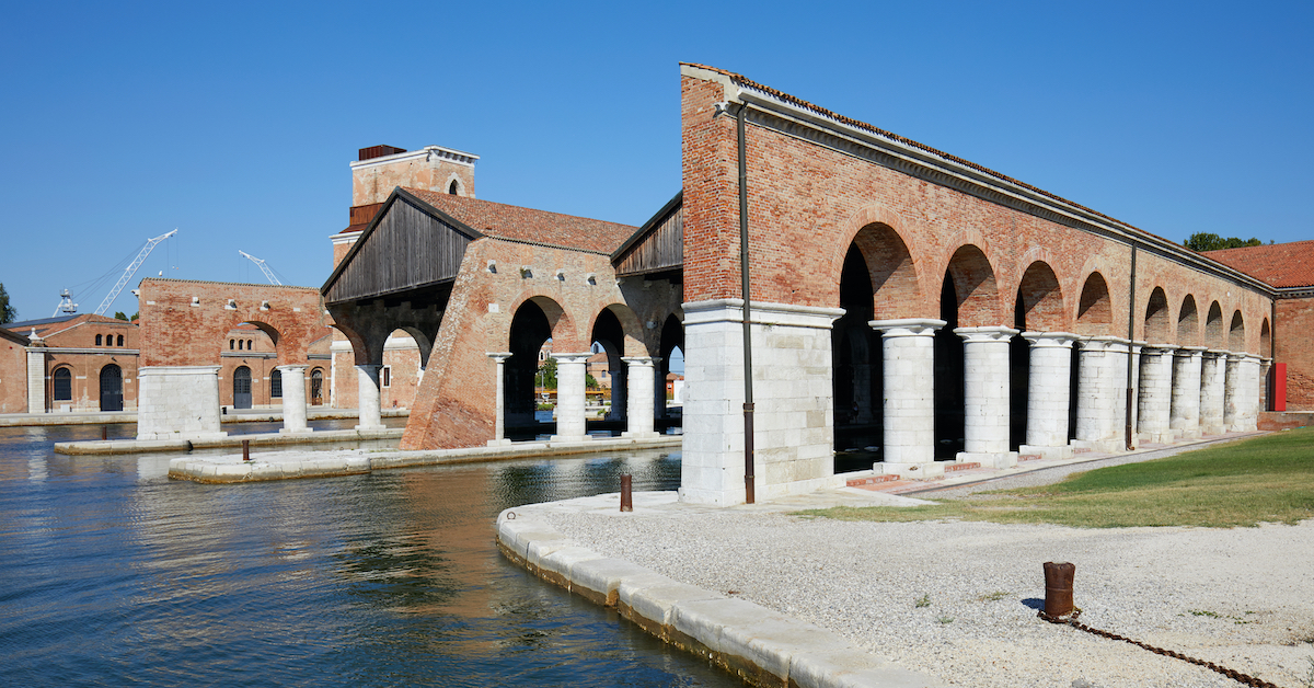 Stone archways lining blue water leading into the Venetian Arsenal